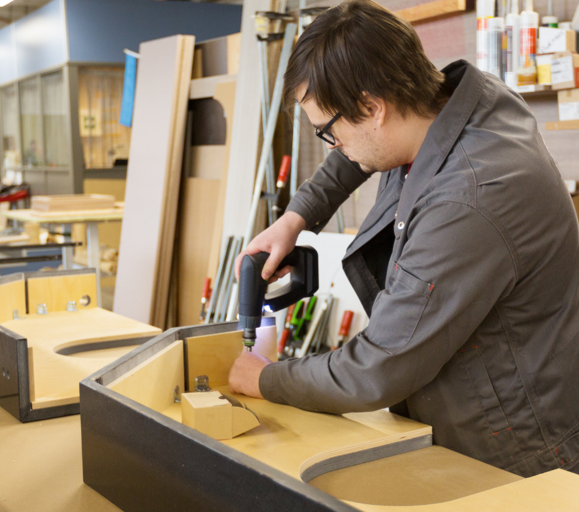 Assemblagemedewerker werkt aan een houten constructie in een werkplaats en gebruikt handgereedschap