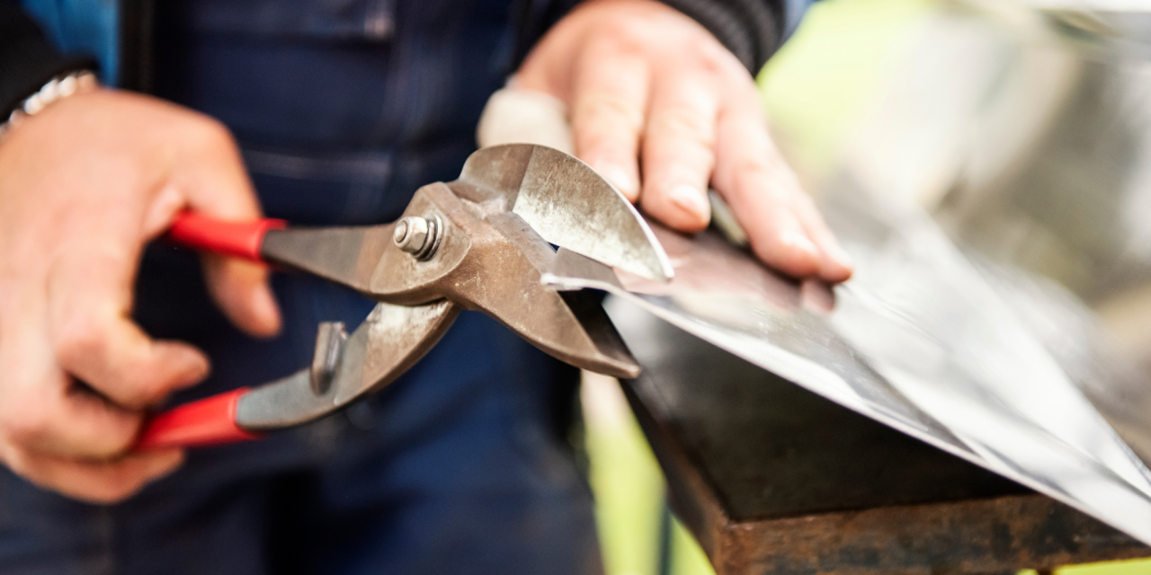 Metaalbewerker knipt metaal met handgereedschap