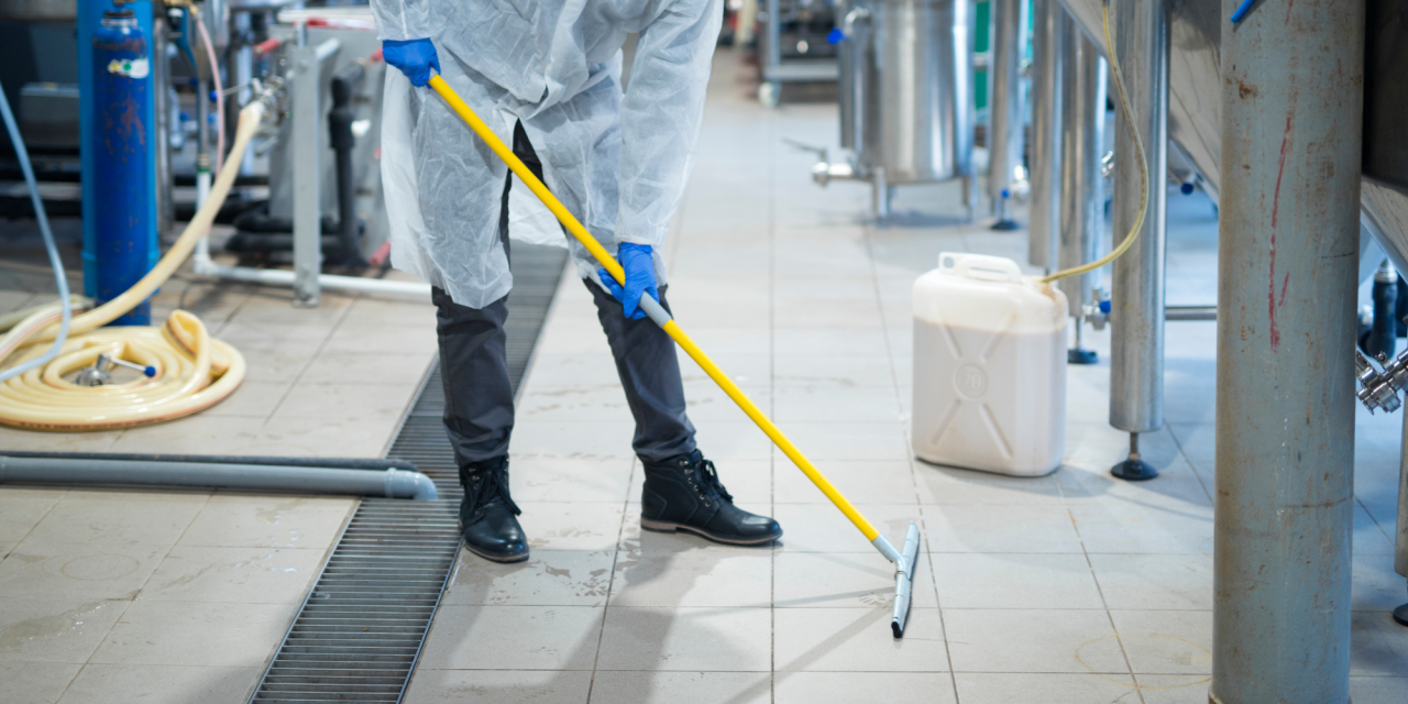 Schoonmaker dweilt vloer in bedrijfsruimte