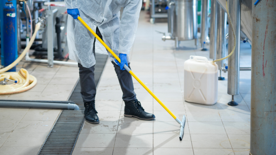 Schoonmaker dweilt vloer in bedrijfsruimte