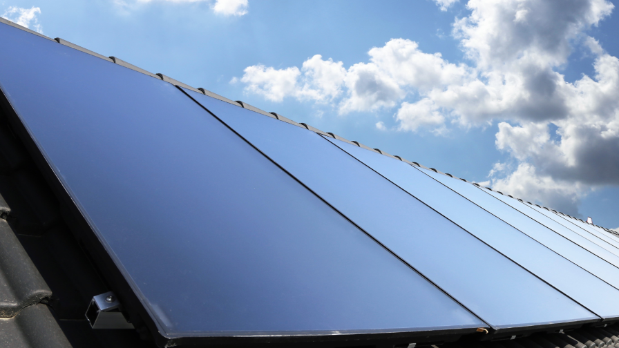 Geplaatste zonnepanelen op dak tegen blauwe lucht.