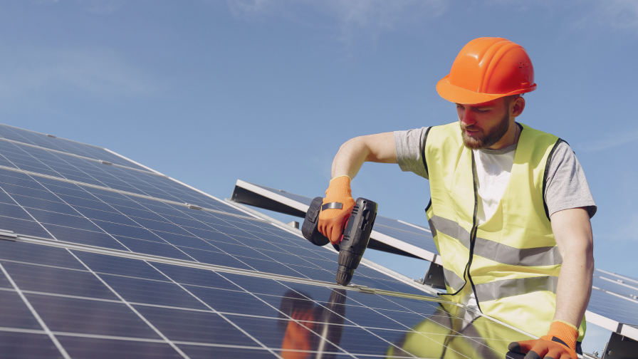 Zonnepanelenmonteur bevestigt paneel op dak