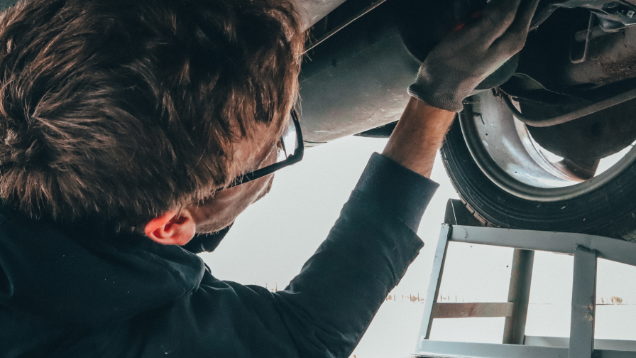 Automonteur die de uitlaat inspecteert