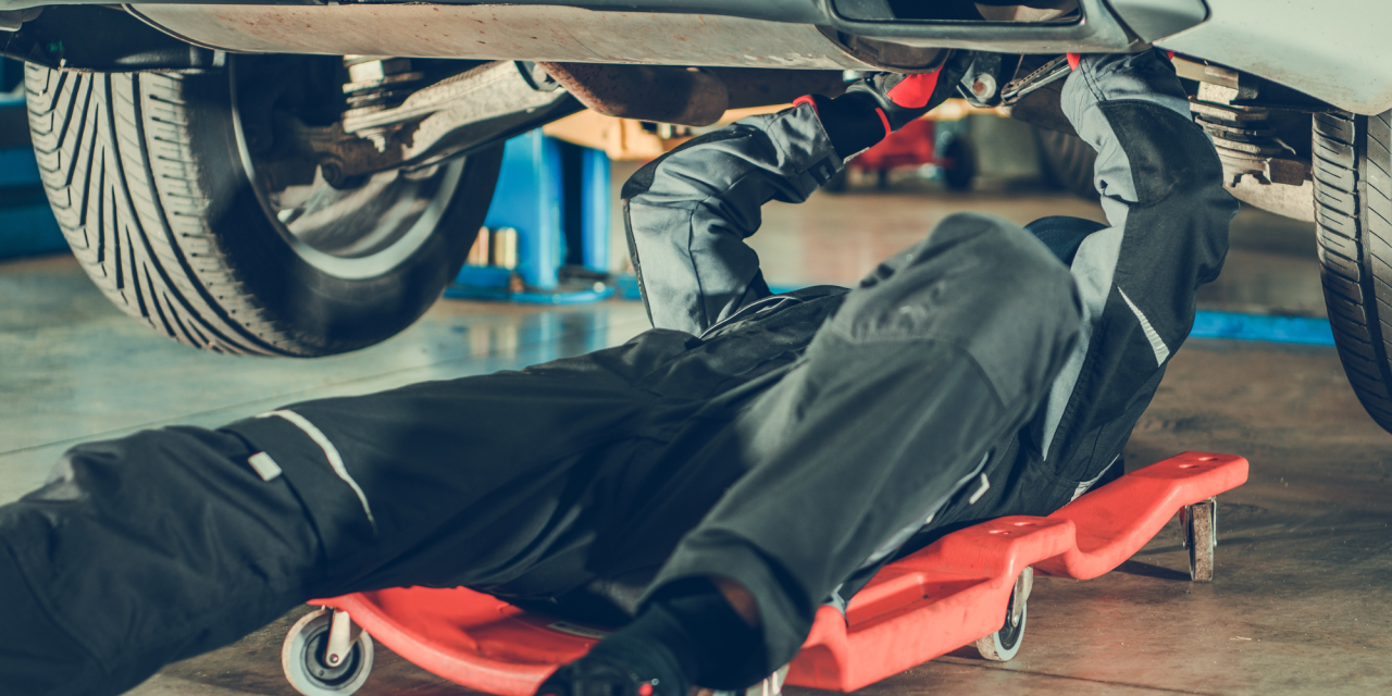 Automonteur die onder een auto aan het sleutelen is