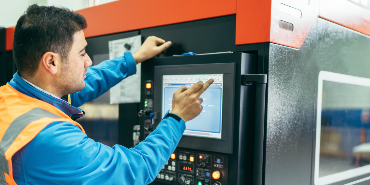 Medewerker bedient digitaal scherm van productiemachine