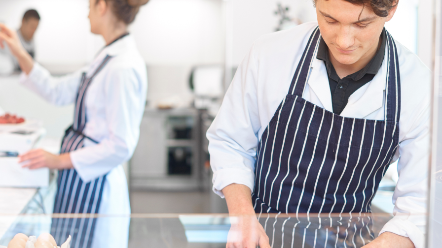 mannelijke medewerker in slagerij en vrouw op achtergrond bedient kassa