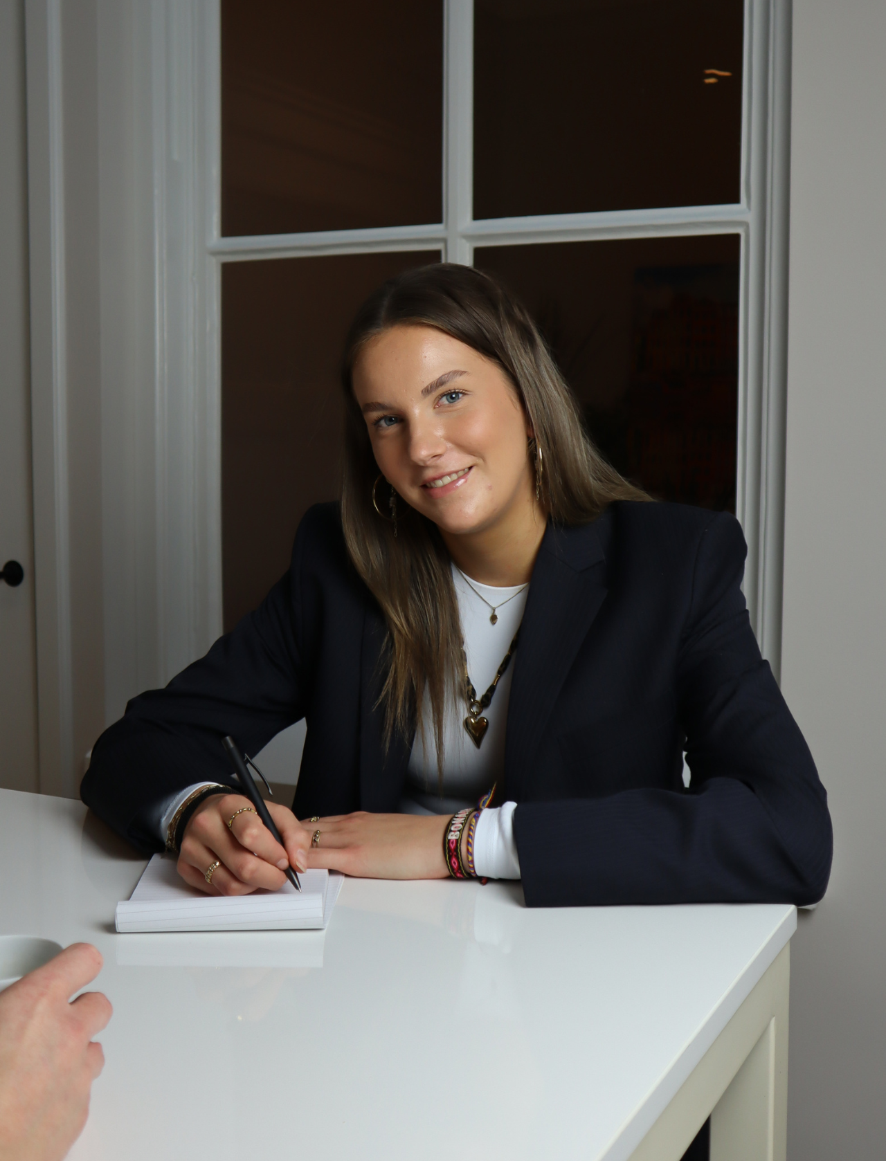 Vrouwelijke recruiter aan tafel met kladblok in gesprek met sollicitant