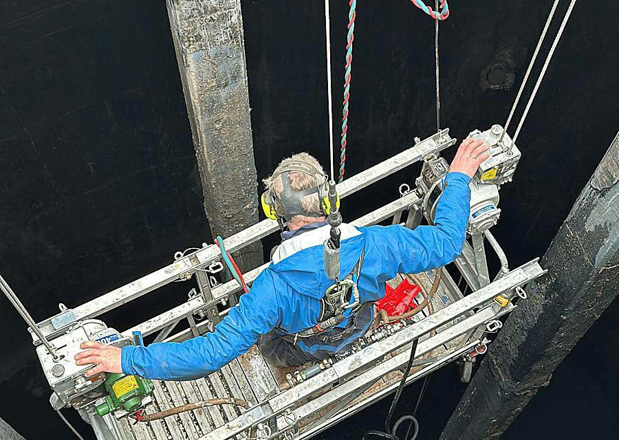 Gevelwerker voert werkzaamheden uit in hangbrug aan gebouw